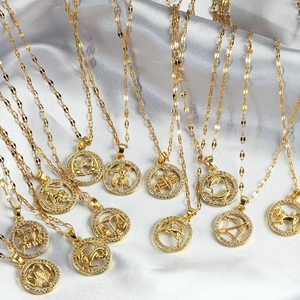 Gold 12 zodiac pendant necklace with cubic zirconia on white silk background