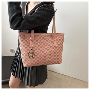 Macro detail of pink tote bag showing M-letter monogram print and metal ring pendant