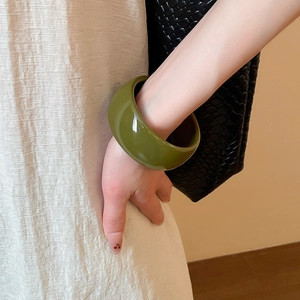 Close-up of olive green acrylic thick round bangle on a model wrist with a stylish texture