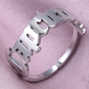 Macro view of silver stainless steel ring with gothic BRAT镂空 cutout design on pink silk