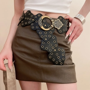 Detail of bohemian retro black leather belt with large gold embossed round buckle and eyelets