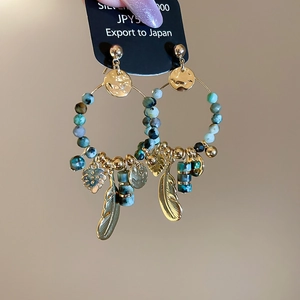 Detailed view of 14K gold plated bohemian hoop earrings with turquoise and feather charms