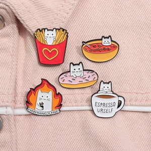 Close-up of cute cartoon cat enamel pins on pink denim, featuring food and snack designs