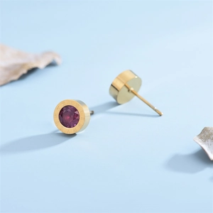 Close-up of golden roman numeral earrings with a faceted purple zircon stone inlay