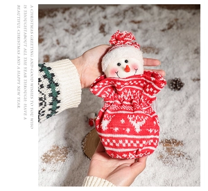 Detail of Christmas snowman knitted drawstring gift bag with elk pattern on snow background