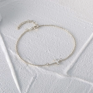 Macro view of S925 sterling silver cross bracelet with adjustable chain on white stone