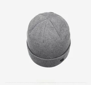 Detailed close-up of dark grey thick knit beanie featuring a round metal logo