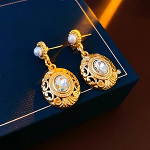 Close-up of vintage gold earrings with pearls and crystal pendant on jewelry box