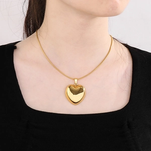 Close-up of a polished golden hollow heart pendant on a delicate snake chain necklace