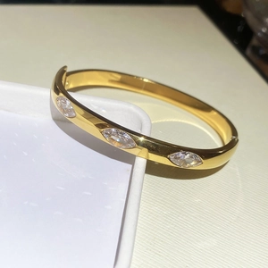 Macro detail of gold oval bangle with three marquise-cut sparkling cubic zirconia stones