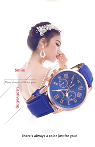 Detail of rose gold Geneva watch featuring blue leather strap and Roman numeral dial