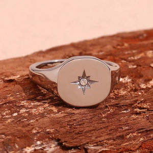 Macro detail of silver starburst signet ring with gemstone on a wood texture