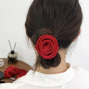 Vue détaillée d'une pince à cheveux rose en velours rouge portée sur un chignon élégant