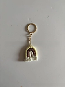 Detail of bohemian handmade woven rainbow keychain with cotton tassels and gold metal ring