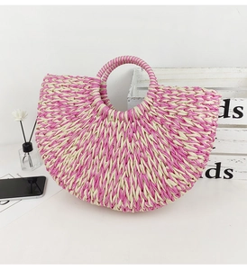 Detail shot of a pink and beige woven straw handbag in semi-circular beach tote design