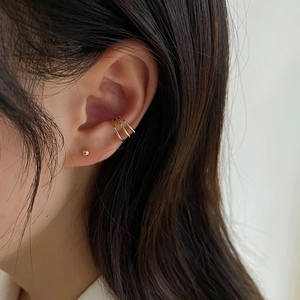 Close-up of a gold triple-layer ear cuff and sphere stud earring on a model