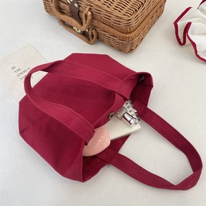 Detailed view of wine red canvas tote showing interior capacity and magnetic metal clasp