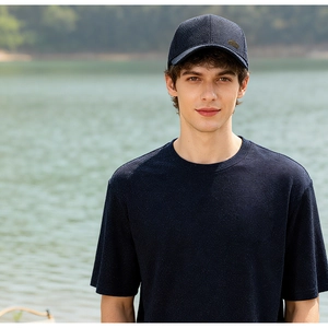 Close-up of a dark navy baseball cap and matching t-shirt worn by a model near a lake