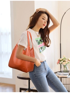 Asian model wearing a large orange litchi grain leather tote bag in a cozy home setting
