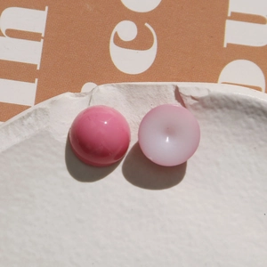 Macro view of pink heart and round resin beads on a white ceramic plate for DIY crafts