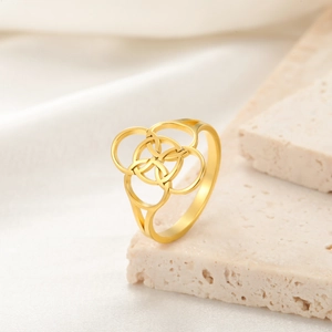 Detailed close-up of a gold geometric flower ring on stone with silk background