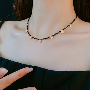 Gros plan d'un collier ethnique perlé avec de petits pendentifs dorés sur le cou