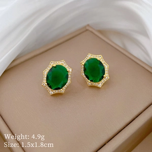 Close-up of emerald green oval earrings with gold trim and weight parameters
