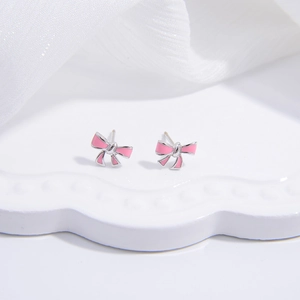 Macro shot of S925 sterling silver pink enamel bow stud earrings on a white tray