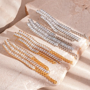 Boucles d'oreilles pendantes de luxe en or et argent avec zircons sur fond de pierre