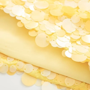 Close-up detail of shiny bright yellow sequins stitched on matching lightweight fabric