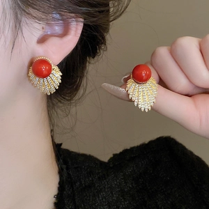 Macro detail of red pearl fan earrings with sparkling zircon crystals in gold plating