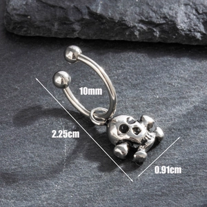 Hip hop titanium steel skull horseshoe ring earrings on a dark textured stone background
