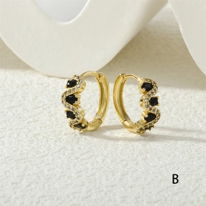 Macro shot of gold hoop earrings with oval black stones and sparkling crystal pavé