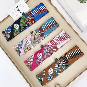 Detail view of multi-color twilly scarves with feather patterns in a gold-rimmed tray