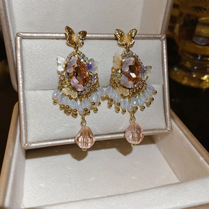 Macro view of vintage butterfly earrings with champagne crystal and pink drop pendant