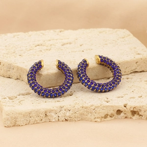 Chic gold C-shape hoop earrings paved with deep blue rhinestones on a stone surface