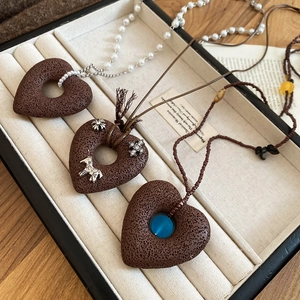 Detail of stone heart necklaces with silver horse charm and blue bead on woven cord