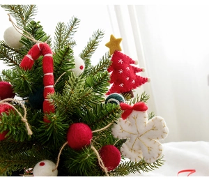 Macro shot of wool felt Christmas ornaments like candy canes and stars on a green pine tree