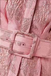 Close-up of pink jacquard fabric with elegant square buckle belt on a vintage dress