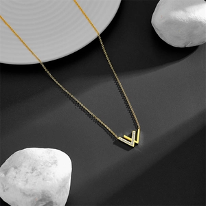 Minimalist gold-plated W letter necklace with shimmering cubic zirconia on black texture