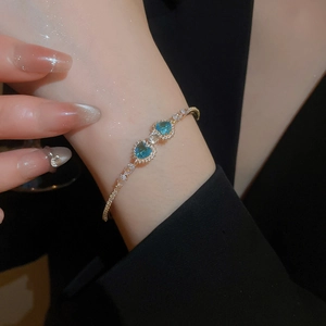 Detailed close-up of a luxury gold cuff with blue heart-shaped gems and zircons