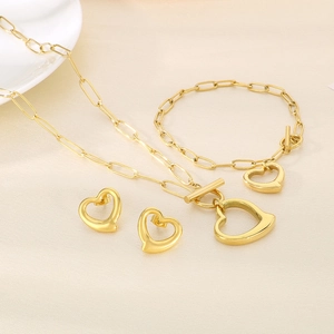 Detailed view of hollow heart jewelry set with paperclip chain in gold plated finish