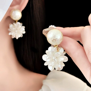 Detailed view of elegant gold pearl drop earrings with 3D white flower petals on model