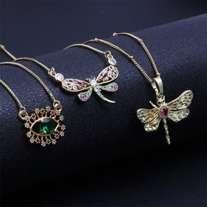 Golden necklaces with colorful dragonfly and evil eye pendants on a luxury black display