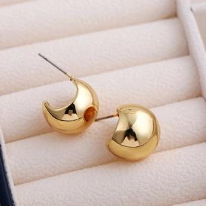 Detailed view of chunky golden C-shaped hoop earrings resting in a soft velvet jewelry box