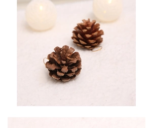 Close-up of two natural pine cone ornaments with gold hanging strings on white fur