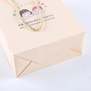Detail of pink children's paper gift bag with golden spiral handles and cartoon prints