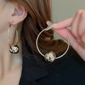 Macro shot of large polished silver hoop earrings with sphere beads on a female model