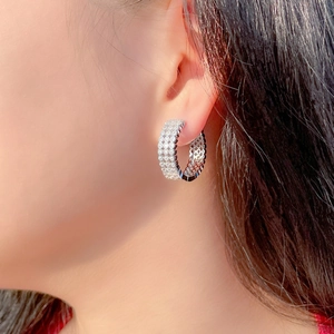 Close-up of silver hoop earring with paved zircon stones worn by a model
