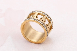 Detail of wide gold plated ring with cutout figure motifs and double row zircons